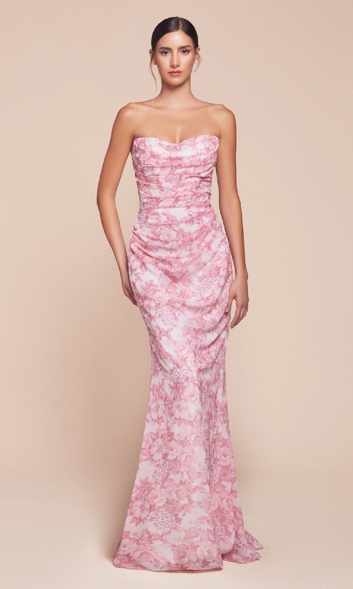 A woman stands facing forward in the Ladivine 7445, a strapless long floral-print prom dress in pink, set against a plain beige background.